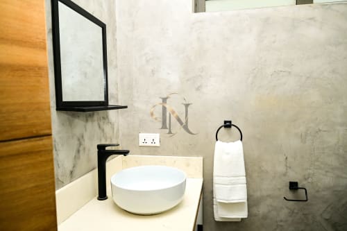 Salle de bain moderne de la villa Nora à Gerards & Angel, Grand Baie avec lavabo blanc, robinetterie noire et murs en marbre