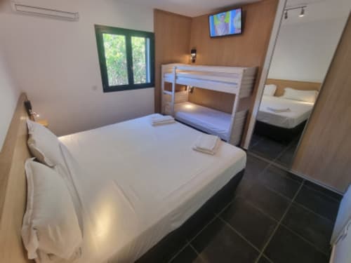 Chambre moderne aux Villas d'A Storia à Zonza avec lit queen-size, lits superposés, TV et vue mer