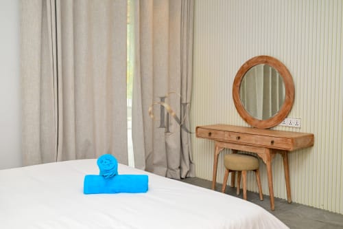 Chambre de la villa Nora à Gerards & Angel, Grand Baie avec vanité en bois, miroir rond et décoration bleue sur le lit