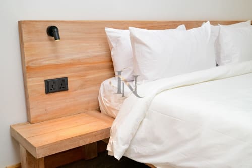 Chevet moderne en bois avec oreillers blancs, prises noires et lampe de lecture à la villa Nora, Grand Baie
