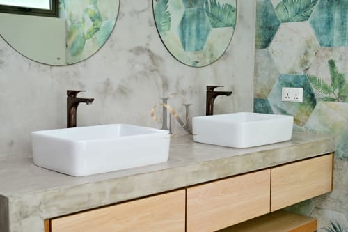 Salle de bains moderne avec deux vasques rectangulaires blanches, robinetterie bronze et décoration botanique tropicale chez Gerards & Angel