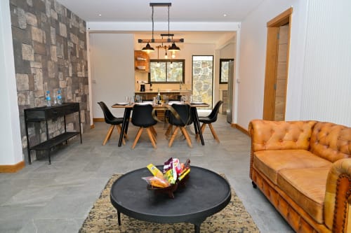 Élégant espace de repas et salon à la villa moderne Gerards & Angel à Grand Baie, avec canapé cuir, table basse ronde noire et touches de bois