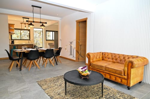 Espace de vie de la villa Nora à Gerards & Angel, Grand Baie avec canapé en cuir caramel, table ronde noire et coin repas