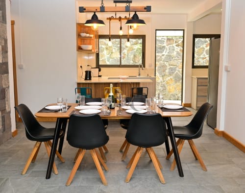 Salle à manger moderne de la villa Gerards & Angel à Grand Baie avec table en bois, chaises noires et cuisine ouverte
