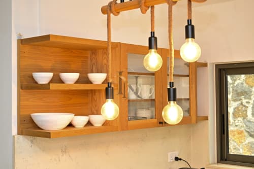 Armoire de cuisine en bois avec bols blancs et quatre luminaires suspendus à détails de corde à la villa Nora, Gerards & Angel, Grand