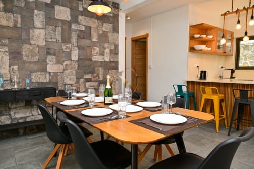 Élégante salle à manger de la villa Nora, Gerards & Angel, Grand Baie avec table en bois, mobilier contemporain et mur en pierre.