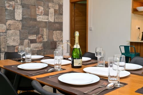 Table de salle à manger élégamment dressée avec une bouteille de champagne, assiettes blanches et couverts à la villa Gerards & Angel de Grand Baie