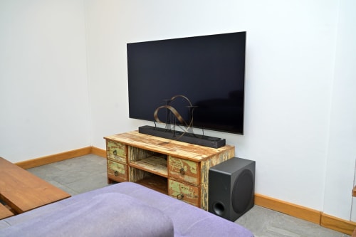 Chambre de la villa Nora avec meuble TV en bois, écran plat et enceinte noire à Grand Baie