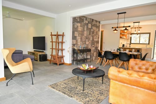 Salon moderne de villa avec canapé en cuir orange, cheminée, coin repas et luminaires suspendus dans la suite Nora chez Gerards