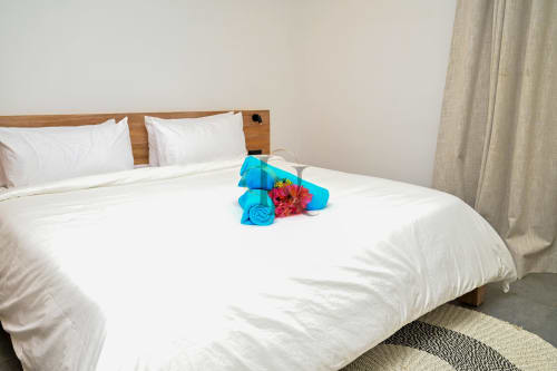 Serviette bleu roulée avec fleur rose sur lit blanc à la villa Gerards & Angel à Grand Baie