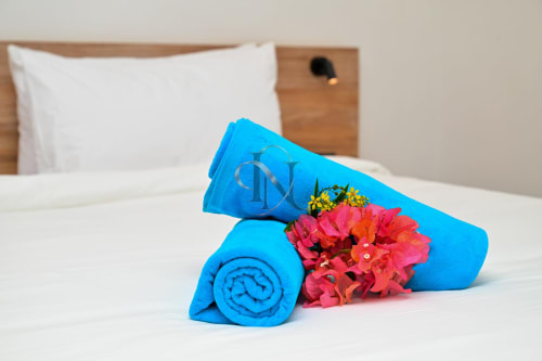 Serviettes bleues roulées avec fleurs rouges sur le lit de la villa Gerards & Angel à Grand Baie