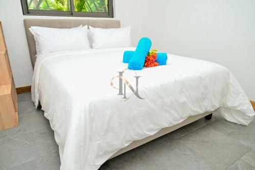Chambre moderne de la villa Nora à Grand Baie avec literie blanche, serviettes bleues et fleurs fraîches