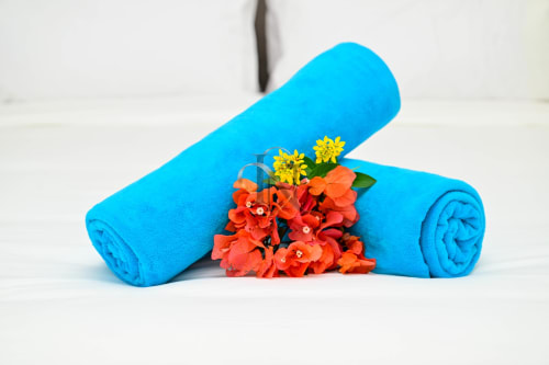 Serviettes bleues roulées aux fleurs rouge et jaune à la villa Gerards & Angel à Grand Baie