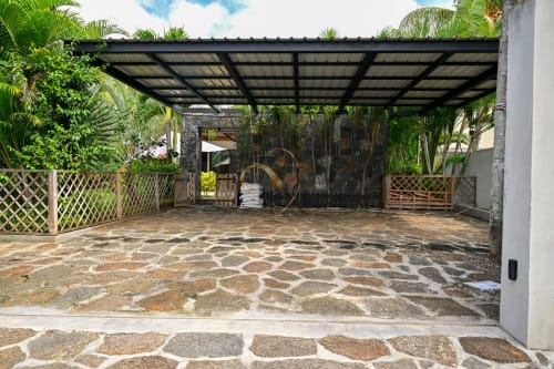Villa Nora Gerards & Angel à Grand Baie : cour pavée avec portails à treillis, palmiers et pergola moderne au toit noir