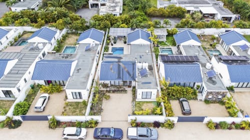 Vue aérienne de la villa Gerards & Angel à Petit Raffray : toit bleu, piscine, panneaux solaires et accès plage.