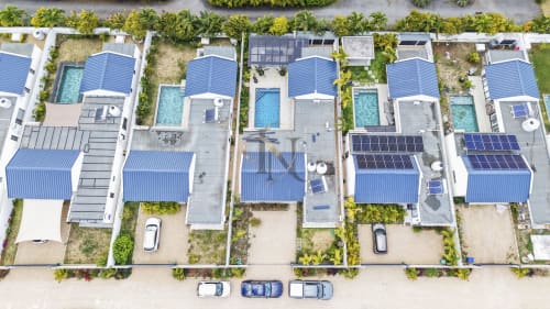 Vue aérienne des villas Gerards & Angel à Petit Raffray avec toits bleus, piscines privées, panneaux solaires et aménagement paysager