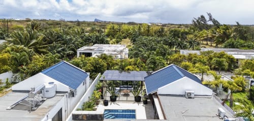 Vue aérienne de la Villa No. 5 Coin des Zils à Petit Raffray avec bungalows aux toits bleus, piscine et paysage bordé de palmiers.