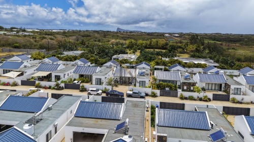 Vue aérienne des villas blanches modernes aux toits métalliques bleus du resort Gerards & Angel à Petit Raffray, Île Maurice, entourées