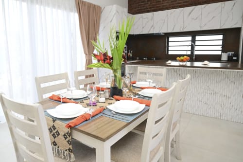Salle à manger de villa moderne avec chaises blanches, table en bois et cuisine ouverte à Gerards & Angel, Maurice