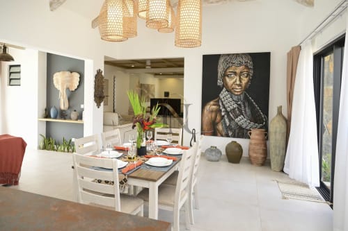 Salle à manger contemporaine de la villa Gerards & Angel avec mobilier blanc, portrait, luminaires suspendus tressés et éléments décorlatifs