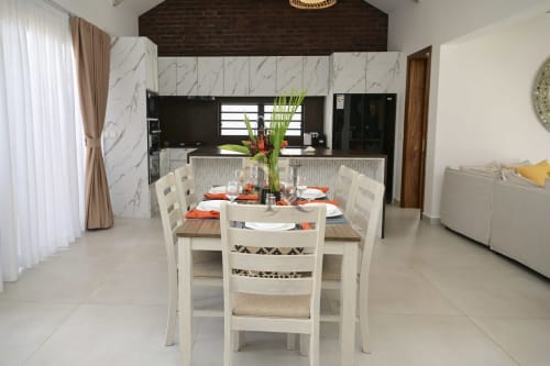 Élégante salle à manger de villa moderne chez Gerards & Angel avec cuisine en marbre, chaises blanches et fleurs fraîches au Petit Raffray.