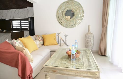 Salon moderne de villa avec canapé crème, coussins jaunes, miroir décoratif et table basse à Gerards & Angel, Île Maurice