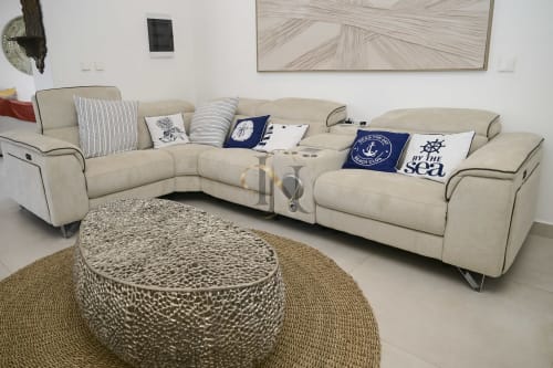 Canapé sectionnel crème avec coussins nautiques et ottoman à motifs dans le coin salon de la Villa Coin des Zils chez Gerards & Angel