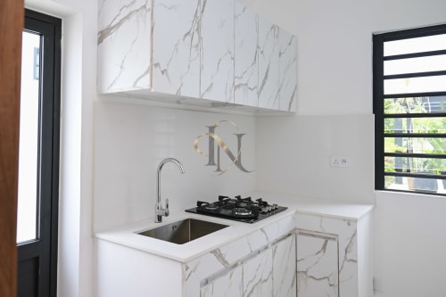 Cuisine moderne de la villa Gerards & Angel avec comptoirs en marbre, cuisinière au gaz, évier et art mural aux initiales de designer