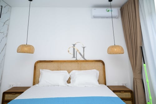 Chambre moderne de la villa Gerards & Angel avec luminaires suspendus tressés, lit en bois, literie blanche et climatisation