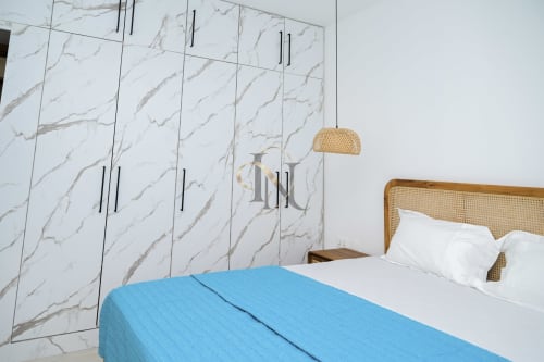 Chambre élégante de la villa Gerards & Angel avec dressing en marbre, suspension en rotin et plaid bleu