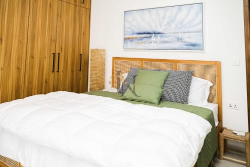 Chambre moderne de la villa Gerards & Angel avec lit en bois, linge de lit vert et tableau de voilier sur murs blancs