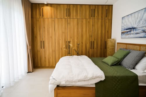 Chambre moderne de la villa Gerards & Angel avec armoire en bois, literie verte, oreillers blancs et tête de lit en rotin à Petit