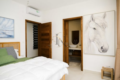 Chambre moderne de la villa Gerards & Angel à Maurice avec lit blanc, portes en bois, climatisation et tableau équestre