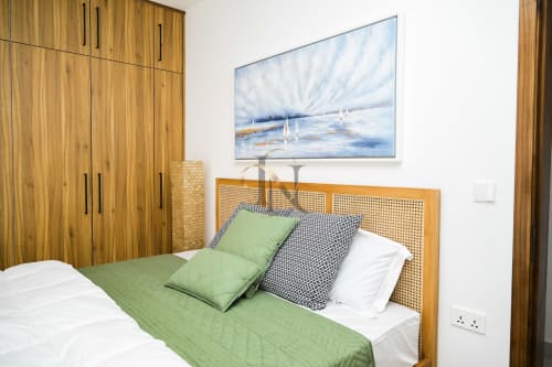 Chambre moderne à la villa Gerards & Angel avec armoire en bois, tête de lit en rotin, literie verte, art nautique et blanc