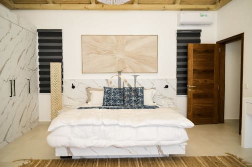 Chambre moderne de la villa Gerards & Angel avec accents en marbre, literie blanche, oreillers à motifs foncés et porte en bois