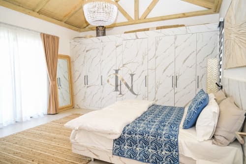 Chambre spacieuse de la Villa No. 5 Coin des Zils à Petit Raffray avec armoire en marbre, poutres en bois et literie à motifs bleus