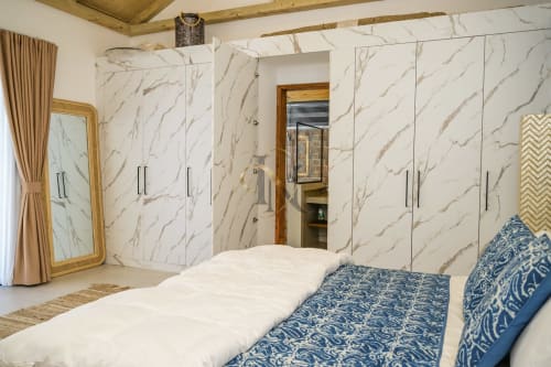Chambre luxueuse à la villa Gerards & Angel avec murs en marbre, literie à motifs bleus et garde-robe moderne à l'Île Maurice