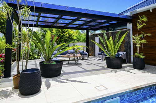 Patio de la villa Gerards & Angel avec pergola noire, plantes tropicales en bacs, coin détente et vue sur la piscine à l'Île Maurice