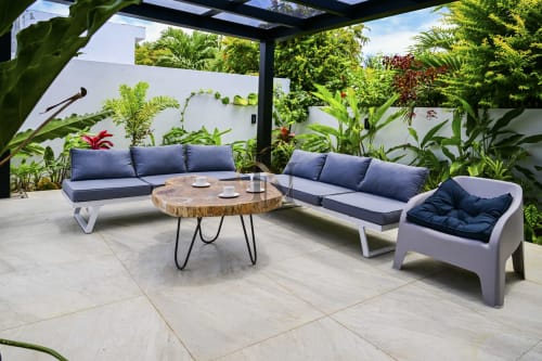 Terrasse élégante avec mobilier bleu marine, table en bois naturel et plantes tropicales luxuriantes à la villa Gerards & Angel