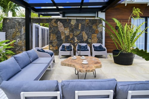 Espace de détente extérieur moderne à la villa Gerards & Angel avec chaises longues bleues, mur en pierre et table en bois à l'Île Maurice
