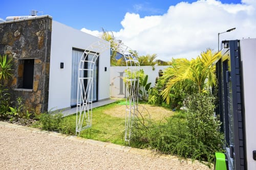 Entrée de la villa Coin des Zils n°5 chez Gerards & Angel à Petit Raffray, avec voûte blanche, plantes tropicales et style moderne