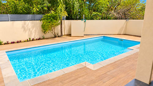 Sparkling blue rectangular swimming pool with wooden decking at Gerards & Angel's Martello Residence Apt 1 in La Preneuse,