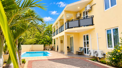Martello Residence Apt 1 at Gerards & Angel, La Preneuse - Yellow apartment with pool view, palm trees, and patio