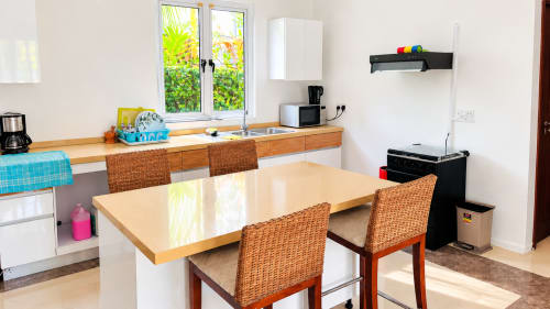 Modern kitchen and dining area at Gerards & Angel apartment in La Preneuse with wooden counters, wicker chairs, and