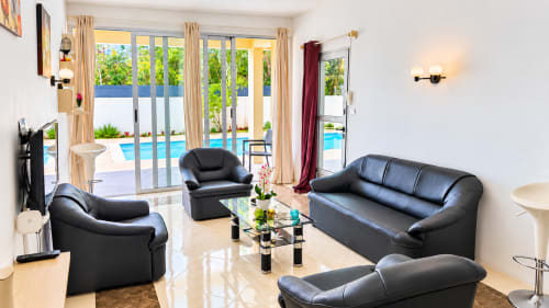 Martello Residence Apt 1 living room with black leather furniture, pool view through glass doors, and modern amenities at