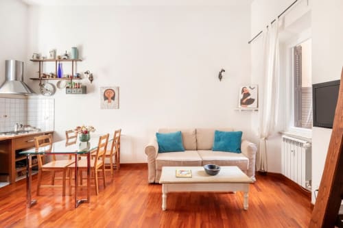 Appartement moderne à Rome avec canapé beige, cuisine, salle à manger, parquets et coussins bleus