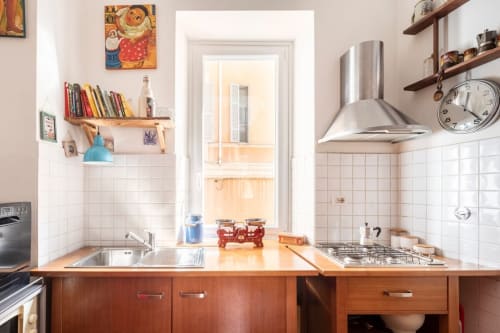 Cuisine lumineuse d'appartement romain avec armoires en bois, électroménagers en acier inoxydable, dosseret blanc et étagères ouvertes