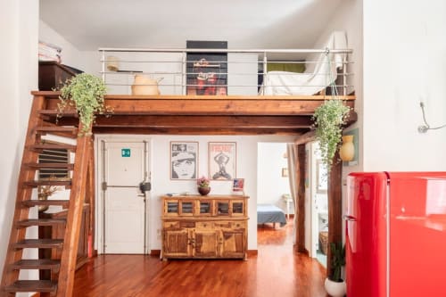 Appartement moderne à Rome avec chambre en mezzanine, poutres en bois, réfrigérateur rouge et escalier hélicoïdal dans un espace ouvert