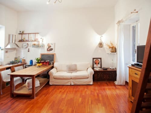 Lumineux séjour romain avec canapé crème, table à manger en bois, kitchenette, parquets et équipements modernes
