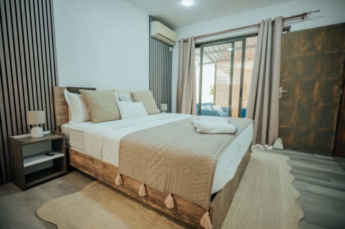 Spacious bedroom at Gerards & Angel villa in Pereybere with queen bed, beige linens, modern striped accent wall, pool view